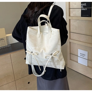 Detail of white glossy PU backpack with cute ribbon bows and silver zippers for women