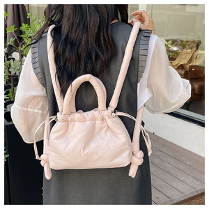 Detail of light pink quilted drawstring backpack with soft padded texture and knot shoulder straps