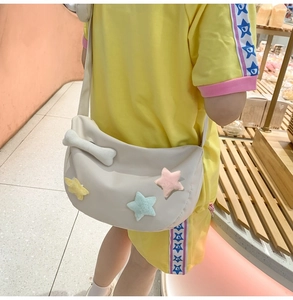 Détail du sac bandoulière croissant en nylon blanc cassé avec étoiles en peluche et os