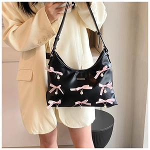 Detail of black PU leather shoulder bag with pink bows and pearl pendants