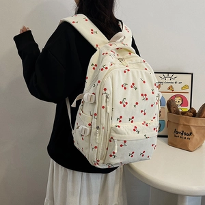 Détail d'un sac à dos en velours côtelé blanc avec motif cerise porté par un mannequin