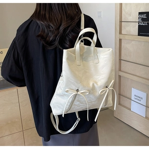 Detail of white pleated PU leather backpack with a sweet bow and adjustable straps