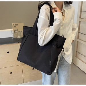 Detail shot of black canvas tote bag with drawstring side and brand label on shoulder