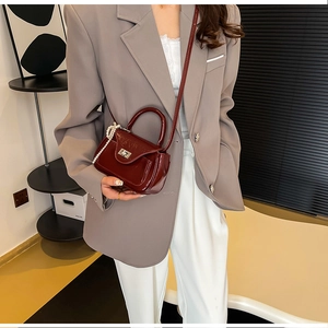Chic burgundy PU leather crossbody bag with pearl bow charm worn by a model in a suit