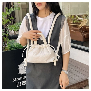 Detail view of a white ruched drawstring crossbody bag with thick padded handles