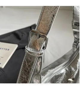 Detail of adjustable silver metallic strap with polished buckle on a stylish PU crossbody bag