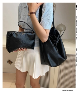 Detail of black PU leather tote set showing the matching clutch and decorative side bow