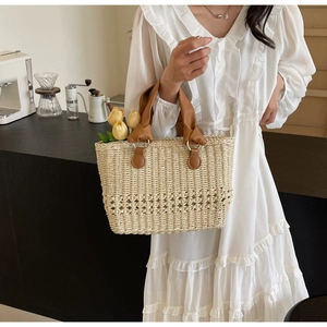 Close-up of beige woven straw tote bag with brown leather handles and hollow texture