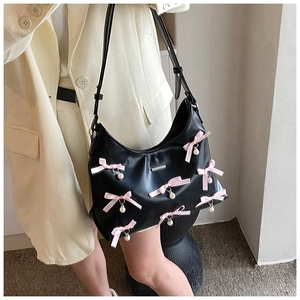 Detail of black PU leather crescent bag with pink bows and pearl charms on model