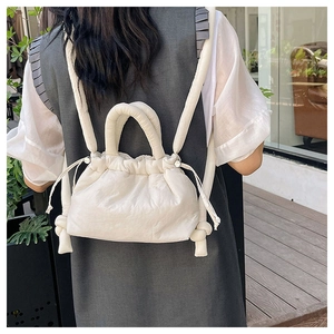 Detailed view of creamy white quilted drawstring backpack showing plush texture and straps