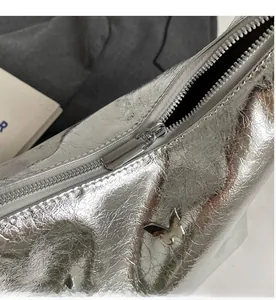 Detail of silver PU leather crossbody bag with metallic texture and butterfly logo