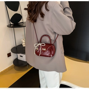 Detail view of burgundy PU leather bag featuring pearl bow and metallic heart pendant