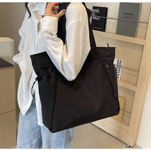 Minimalist black tote bag detail featuring metal eyelets and drawstring on high-density canvas
