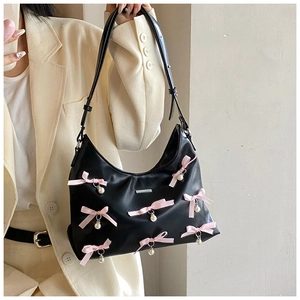 Detail of a black PU crescent bag with pink ribbon bows and hanging pearls on side