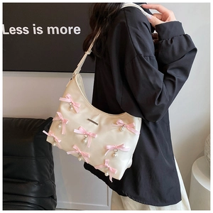 Close-up of cream PU shoulder bag featuring pink silk bows and hanging pearl pendants