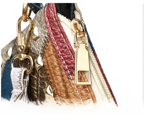 Detail of golden metal zipper and decorative square rivets on multi-color textured handbag
