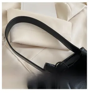 Close-up of a minimalist black PU leather shoulder bag with fine texture and wide strap