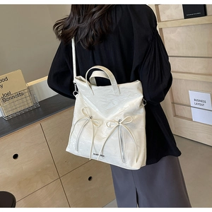 Close-up of beige PU leather tote bag featuring stylish double bow zipper and shiny finish
