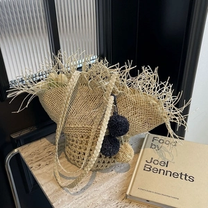 Elegante borsa in paglia intrecciata con bordi sfrangiati e pompon decorativi primaverili