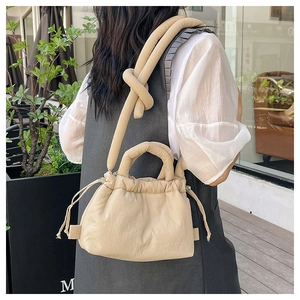 Detail of soft quilted cloud bag in beige featuring adjustable knotted shoulder strap