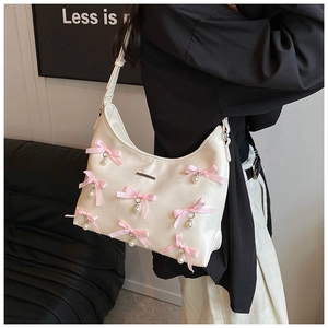 Detail of hobo bag with pink bows and pearl pendants on cream PU leather material