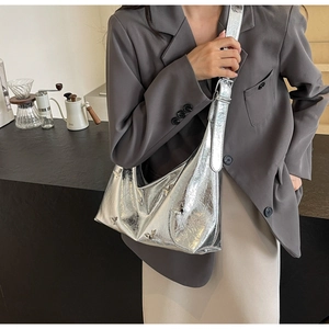 Silver metallic crescent bag with 3D butterfly details and adjustable strap in a cafe setting