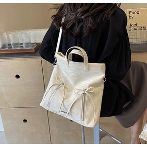 Close-up of beige PU leather tote featuring bow accents and elegant pleated texture