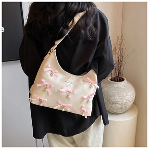 Detail of cream PU leather crescent bag with pink ribbon bows and pearl pendants