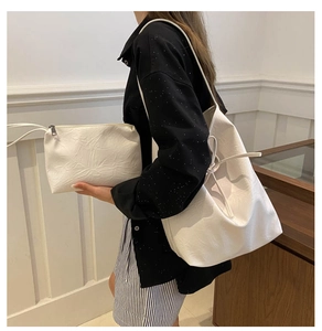 Detailed view of white pleated PU leather tote bag set shown on a shoulder