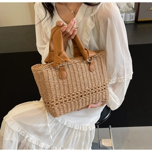 Detail of hand woven straw tote bag with intricate floral patterns and leather handles
