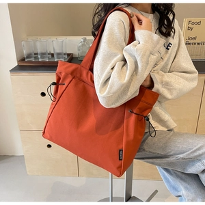 Detail view of the drawstring design and fabric texture on a large brick red canvas tote bag