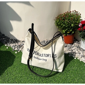 Minimalist canvas tote bag with black leather trim on a scenic outdoor background