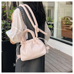 Close-up of a pink puffy cloud bag with drawstrings and knotted rope strap in outdoor setting