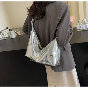 Close-up of silver metallic hobo bag with 3D butterfly ornaments worn by a model