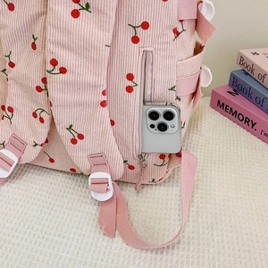 Gros plan détaillé du sac à dos en velours côtelé rose avec motifs cerises et poche