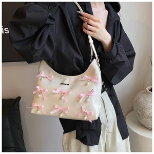 Detailed view of cream PU hobo bag with pink satin bows and hanging pearl charms
