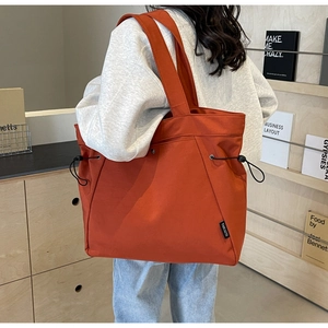 Close-up of caramel canvas tote bag with drawstring detail and woven label on side