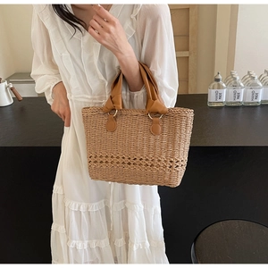 Detail of straw woven handbag featuring brown leather handles and intricate mesh textures