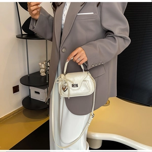 Detail of cream PU crossbody bag with pearl bow and silver heart charm decoration