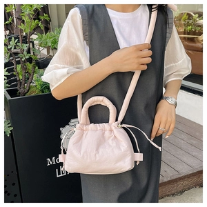 Pink puffer crossbody bag with drawstring closure and soft quilted texture shown on model