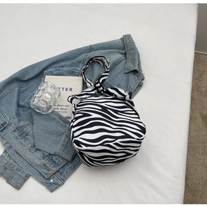 Sac à main nœud en tissu motif zèbre tendance sur fond blanc avec une veste en jean