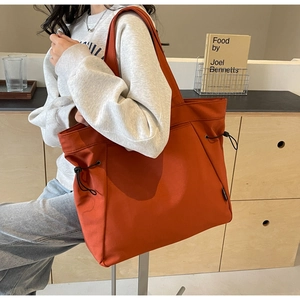 Detail of orange canvas tote bag showing side drawstring and durable fabric texture