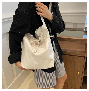 Close-up of white PU shoulder bag featuring pleated texture and bow-tie drawstring detail