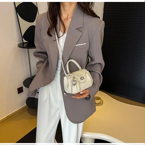 Detail of cream PU leather handbag with pearl bow and silver heart charm on model