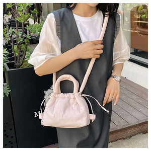 Detail of light pink drawstring cloud bag with quilted texture and thin shoulder strap