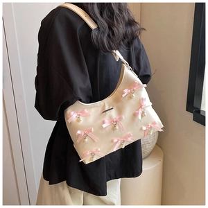 Detail of cream hobo bag featuring pink satin bows and decorative faux pearls