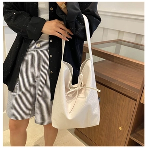 Close-up of white PU leather handbag featuring a stylish bow knot and textured fabric finish
