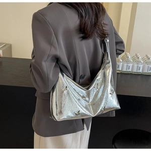 Silver metallic moon hobo bag with 3D butterfly detail worn over a dark grey blazer