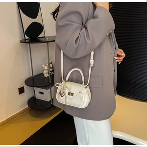 Detail of cream PU leather handbag with pearl bow charm and silver heart pendant