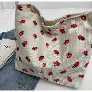 Detailed macro shot of white corduroy tote bag featuring red and green strawberry prints